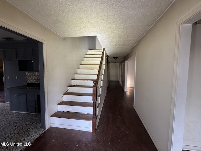 stairs featuring wood-type flooring and a textured ceiling