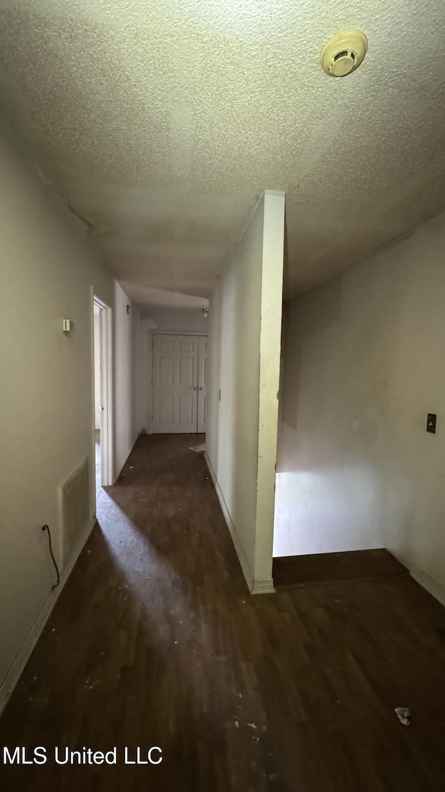 corridor featuring dark hardwood / wood-style floors and a textured ceiling