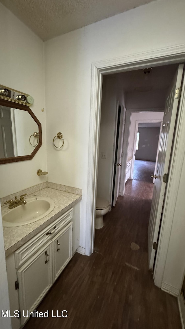 bathroom featuring vanity, a textured ceiling, hardwood / wood-style flooring, and toilet