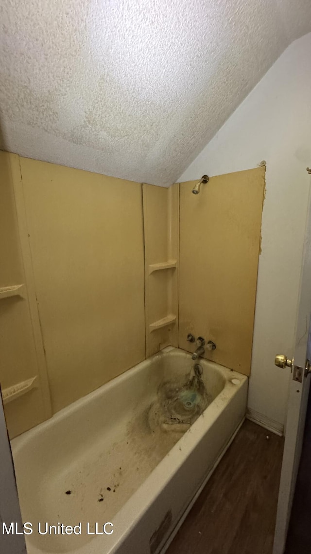 bathroom featuring wood-type flooring, a textured ceiling, shower / tub combination, and lofted ceiling