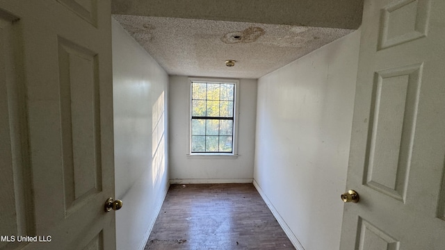 hallway with a textured ceiling and dark wood-type flooring