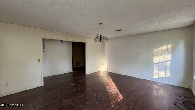 unfurnished room featuring a textured ceiling, dark hardwood / wood-style flooring, and a notable chandelier