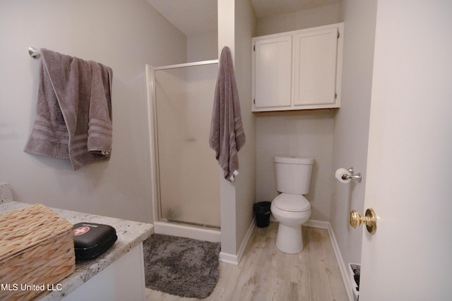 bathroom featuring wood-type flooring, toilet, and an enclosed shower