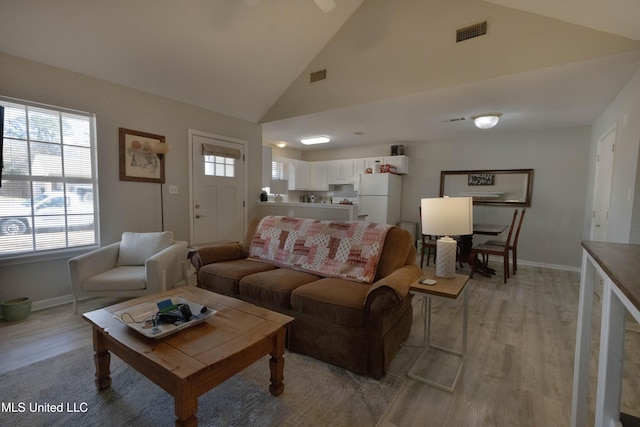 living room with high vaulted ceiling and light hardwood / wood-style flooring