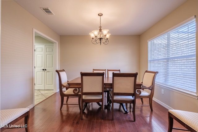 dining space featuring a wealth of natural light, hardwood / wood-style floors, and an inviting chandelier