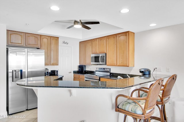 2668 Beach Blvd Unit 1405, Biloxi, MS 39531 - kitchen featuring appliances with stainless steel finishes, ceiling fan, a kitchen breakfast bar, a peninsula, and dark stone countertops