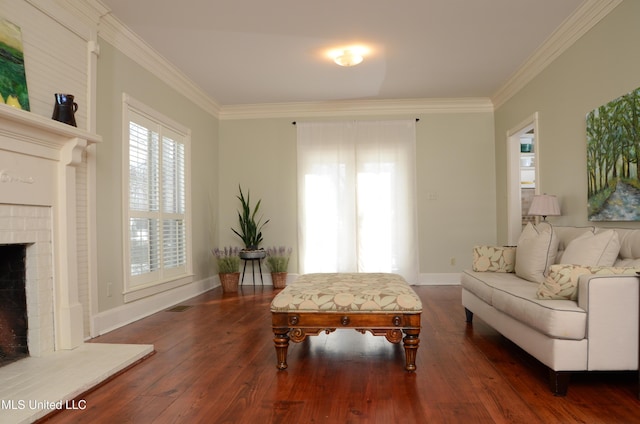 sitting room featuring dark wood-style flooring, visible vents, baseboards, ornamental molding, and a brick fireplace