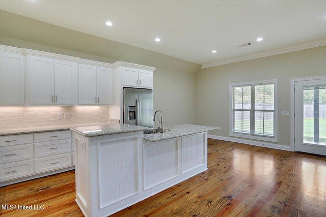 kitchen featuring white cabinetry, light wood-type flooring, a center island with sink, and stainless steel refrigerator with ice dispenser