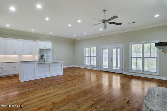 kitchen with a center island with sink, white cabinetry, ornamental molding, dark hardwood / wood-style floors, and stainless steel refrigerator with ice dispenser