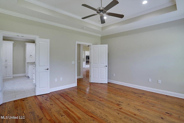 unfurnished bedroom featuring light hardwood / wood-style flooring, ornamental molding, and a raised ceiling