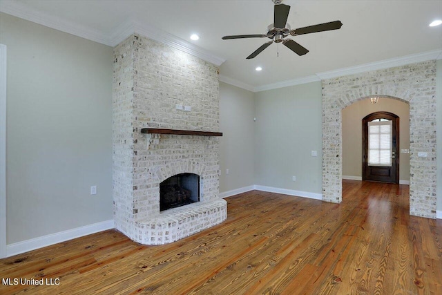 unfurnished living room with a brick fireplace, ornamental molding, hardwood / wood-style flooring, and ceiling fan