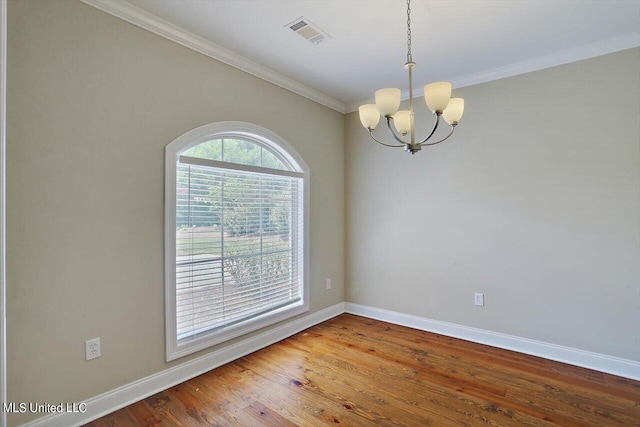 spare room featuring ornamental molding, hardwood / wood-style floors, and an inviting chandelier