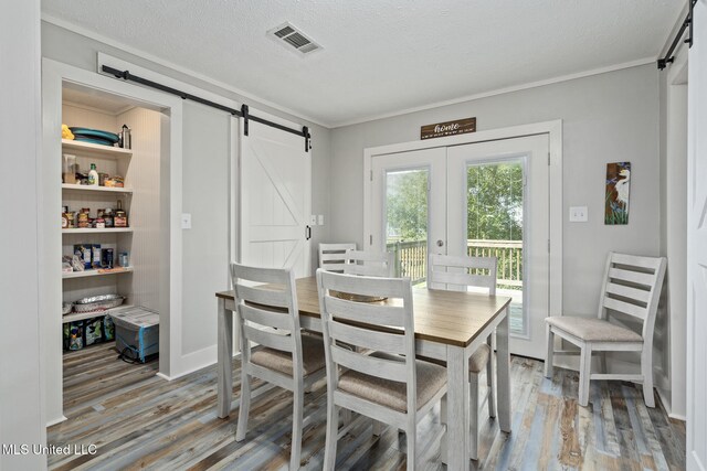 4113 Blue Jay St, Bay Saint Louis, MS 39520 - dining space featuring wood-type flooring, a barn door, crown molding, and a textured ceiling