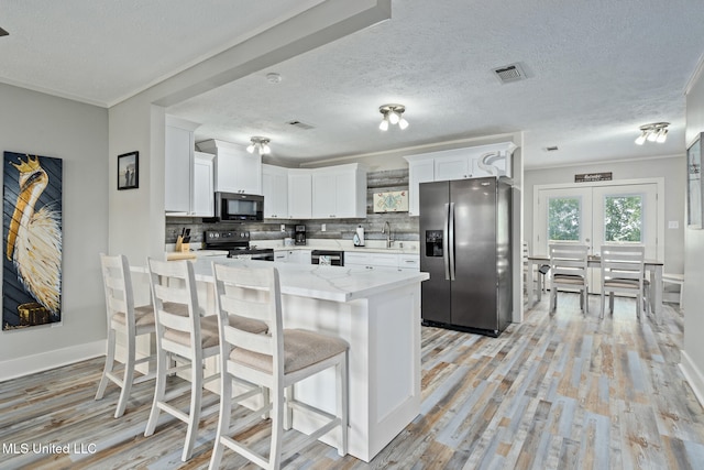 4113 Blue Jay St, Bay Saint Louis, MS 39520 - kitchen featuring white cabinets, stainless steel fridge, backsplash, light hardwood / wood-style floors, and electric stove