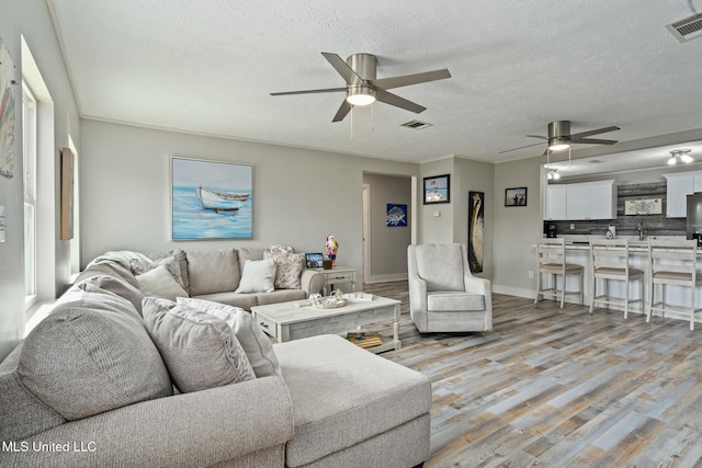 4113 Blue Jay St, Bay Saint Louis, MS 39520 - living room with ceiling fan, ornamental molding, light hardwood / wood-style floors, and a textured ceiling