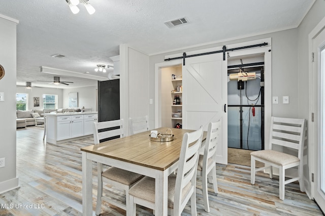 4113 Blue Jay St, Bay Saint Louis, MS 39520 - dining area with ceiling fan, light hardwood / wood-style flooring, a barn door, and a textured ceiling