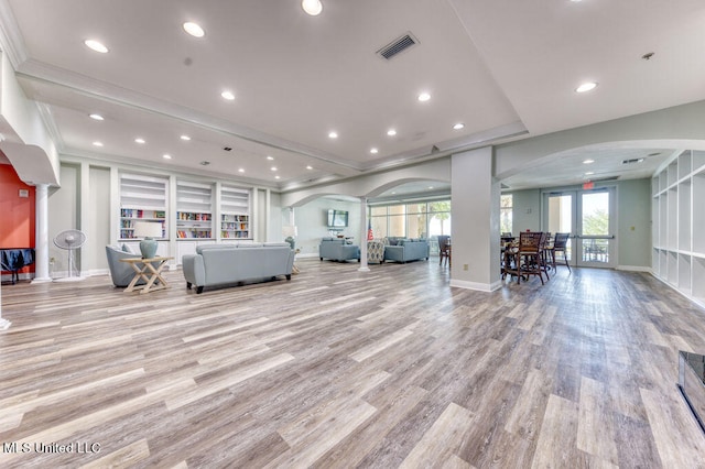 unfurnished living room featuring french doors, crown molding, and light hardwood / wood-style floors