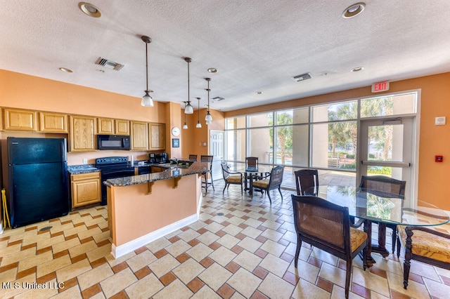 kitchen featuring black appliances, sink, a kitchen breakfast bar, decorative light fixtures, and dark stone counters