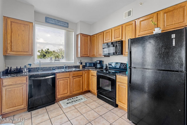 kitchen featuring black appliances, sink, dark stone counters, and light tile patterned floors