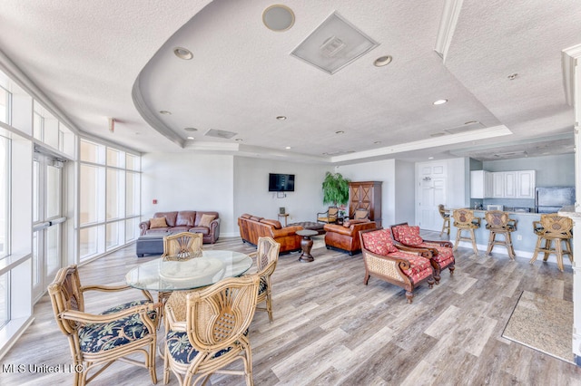 dining area featuring a raised ceiling, a textured ceiling, and light hardwood / wood-style flooring