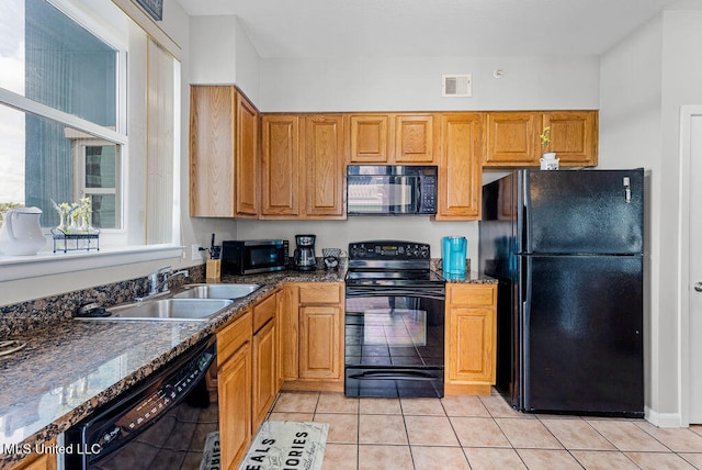 kitchen featuring sink, black appliances, light tile patterned floors, and dark stone counters