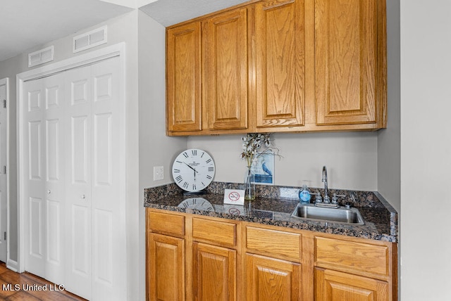 kitchen with hardwood / wood-style flooring, sink, and dark stone counters