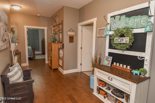 hallway with a textured ceiling and dark hardwood / wood-style flooring