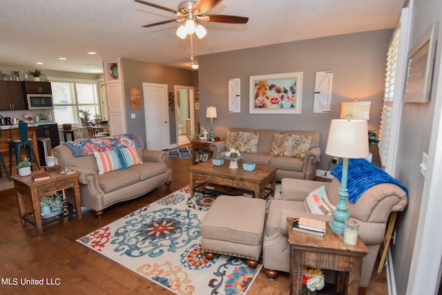 living room featuring dark wood-type flooring and ceiling fan