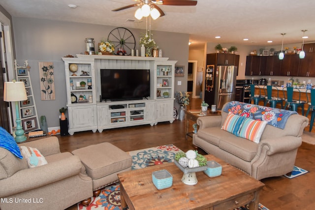 living room featuring dark wood-type flooring, a textured ceiling, and ceiling fan