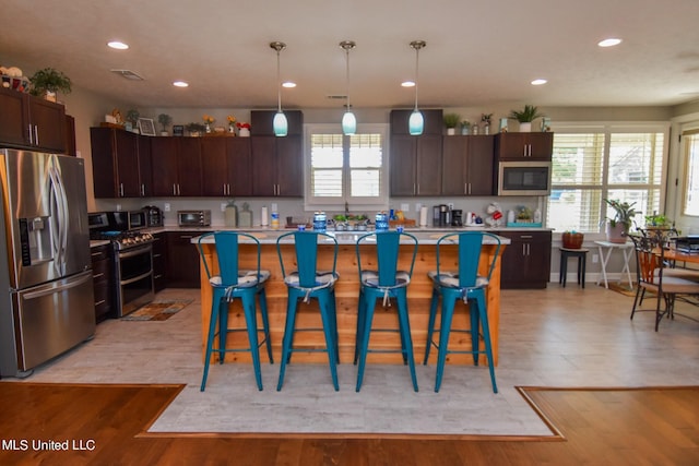 kitchen with light hardwood / wood-style floors, stainless steel appliances, and a kitchen island