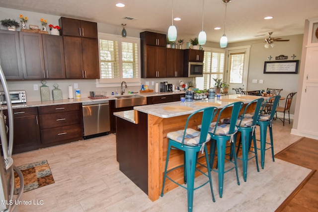 kitchen with sink, a kitchen island, appliances with stainless steel finishes, and plenty of natural light