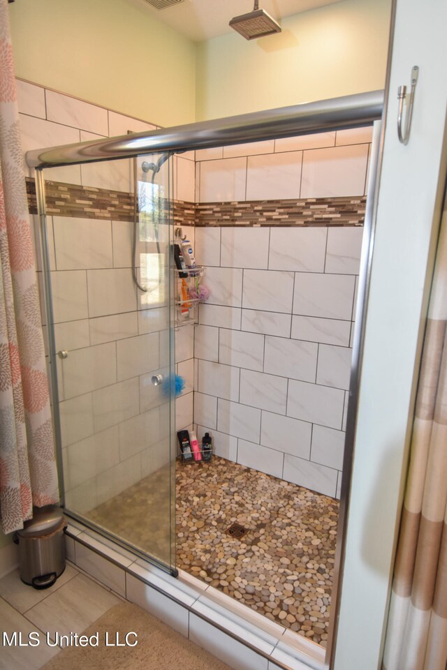 bathroom featuring a shower with shower door and tile patterned flooring