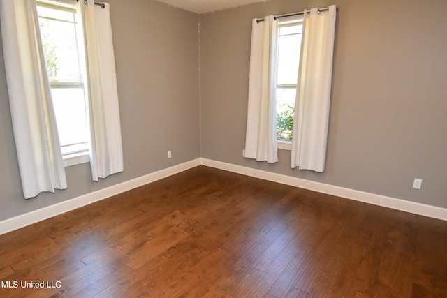 spare room with dark hardwood / wood-style flooring and a wealth of natural light