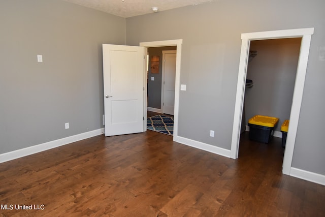 unfurnished bedroom with a walk in closet, dark hardwood / wood-style floors, a closet, and a textured ceiling