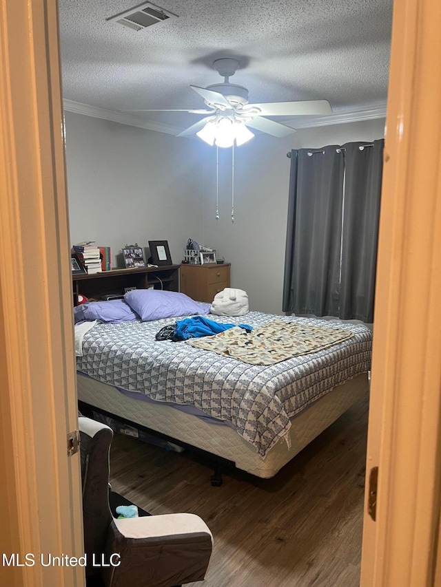 bedroom featuring hardwood / wood-style flooring, ceiling fan, ornamental molding, and a textured ceiling