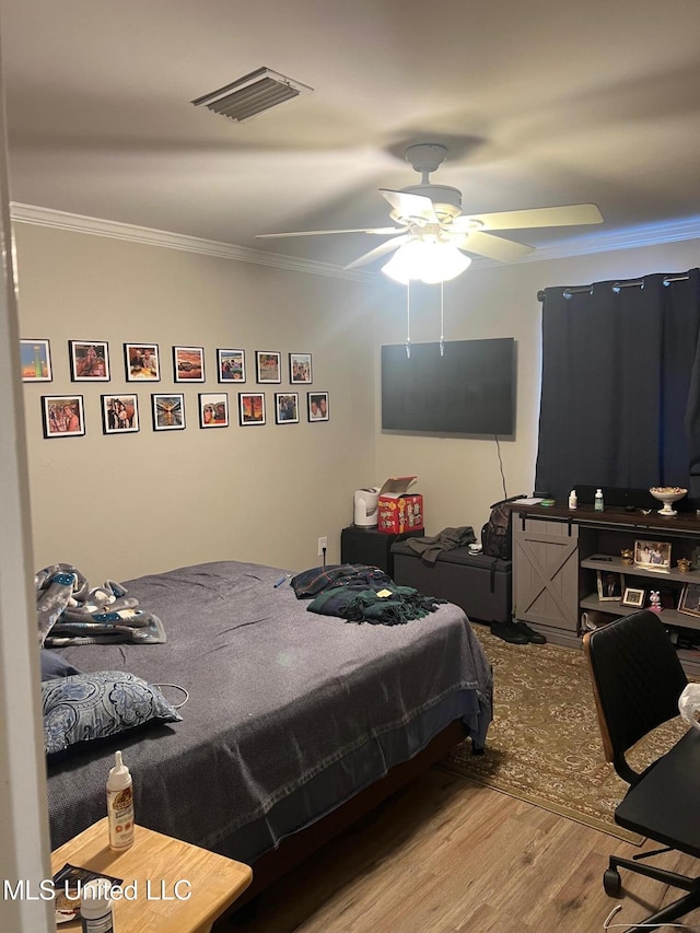 bedroom with hardwood / wood-style flooring, ornamental molding, and ceiling fan