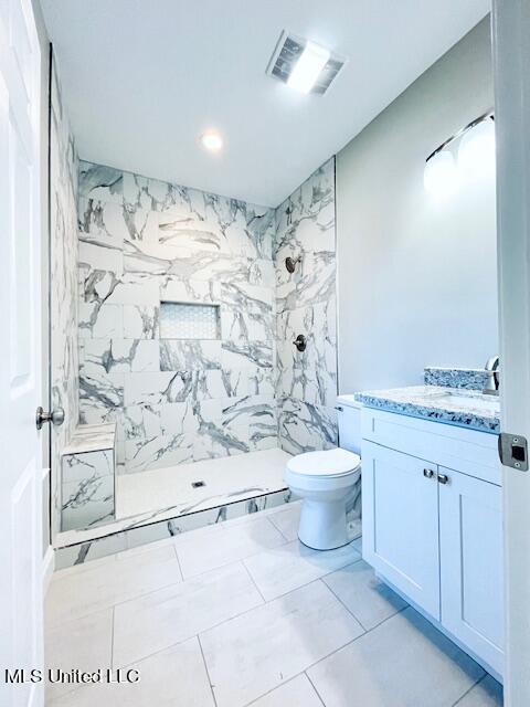 bathroom featuring vanity, walk in shower, toilet, and tile walls