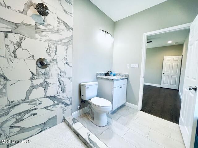 bathroom featuring vanity, toilet, a tile shower, and wood-type flooring