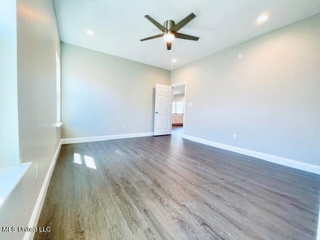 empty room with dark wood-type flooring and ceiling fan