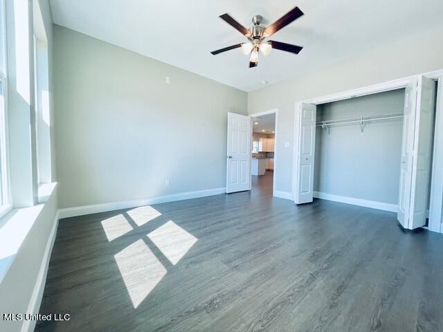 unfurnished bedroom with dark wood-type flooring, ceiling fan, and a closet