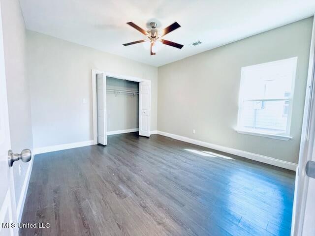 unfurnished bedroom with a closet, dark hardwood / wood-style floors, and ceiling fan