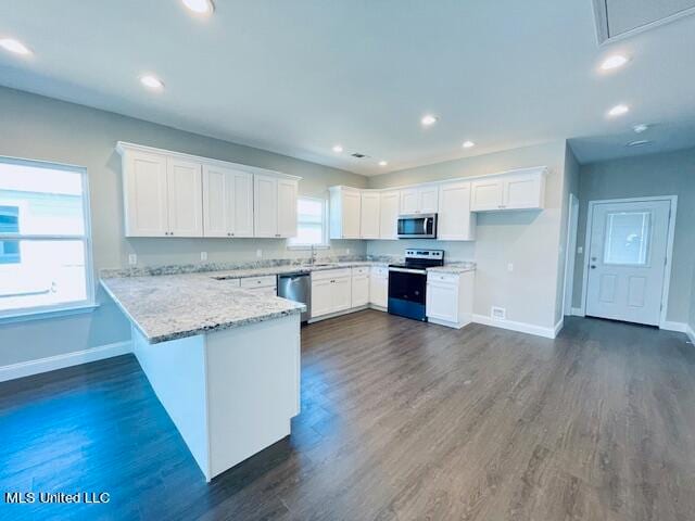 kitchen featuring dark wood-type flooring, appliances with stainless steel finishes, a wealth of natural light, and white cabinets