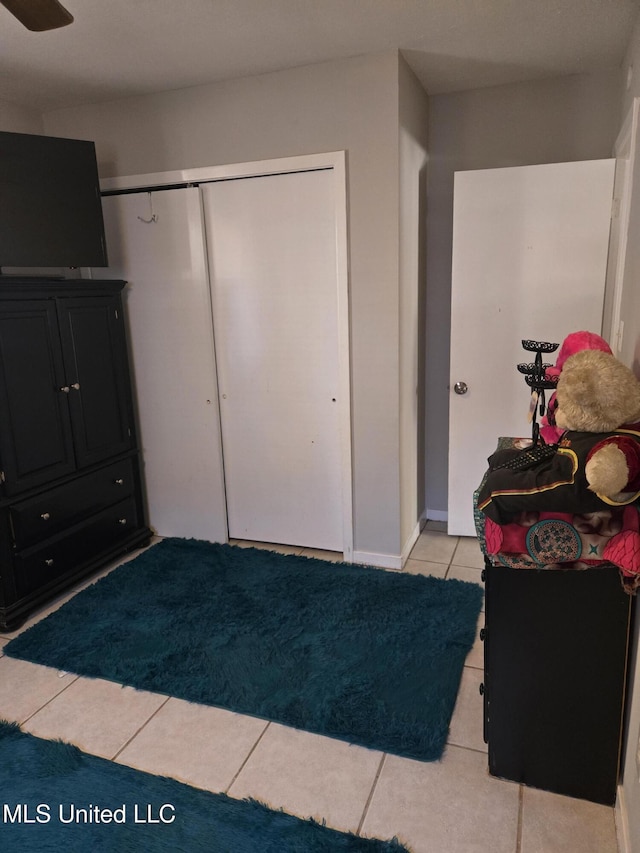 unfurnished bedroom with light tile patterned floors, baseboards, and a closet