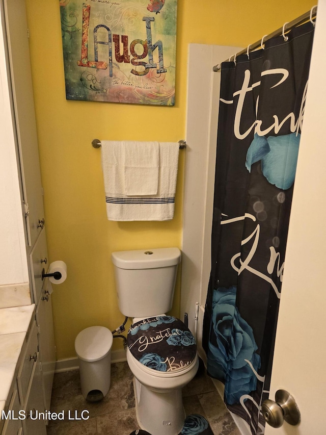 bathroom with a shower with curtain, toilet, vanity, and baseboards