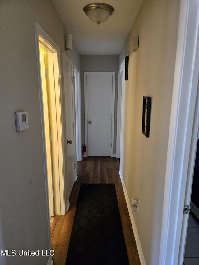 hall featuring baseboards and dark wood-style flooring