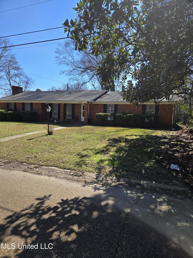 view of front of house featuring brick siding and a front yard