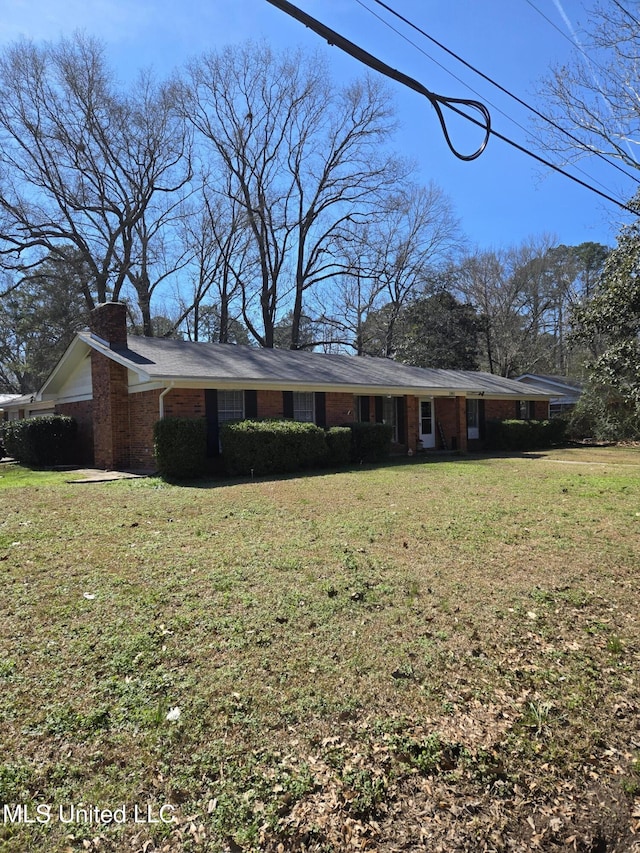 view of front of property with a front lawn, a chimney, and brick siding