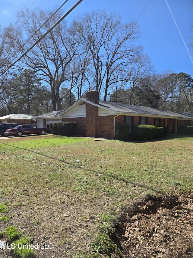 view of side of home featuring brick siding, a lawn, and a chimney