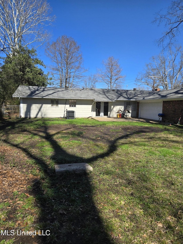 back of property with a garage and a lawn