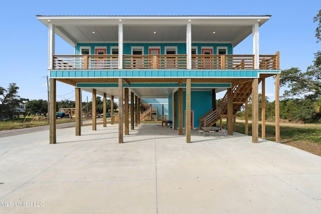 601 E Beach Blvd, Long Beach, MS 39560 - rear view of house with a carport, driveway, stairway, and board and batten siding